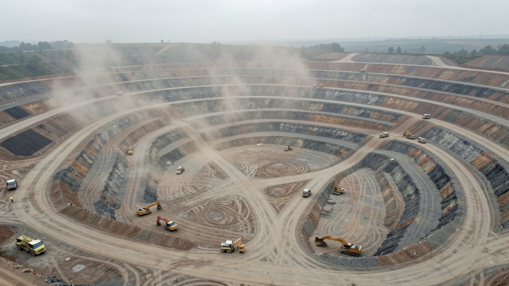 Aerial drone survey of an open-pit mining operation showing 3D terrain model with bench levels, haul roads, and stockpile areas